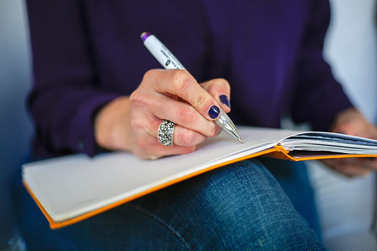 Preparing a first-contact email — Wikimedia Commons A researcher drafts her professor email by hand and laptop