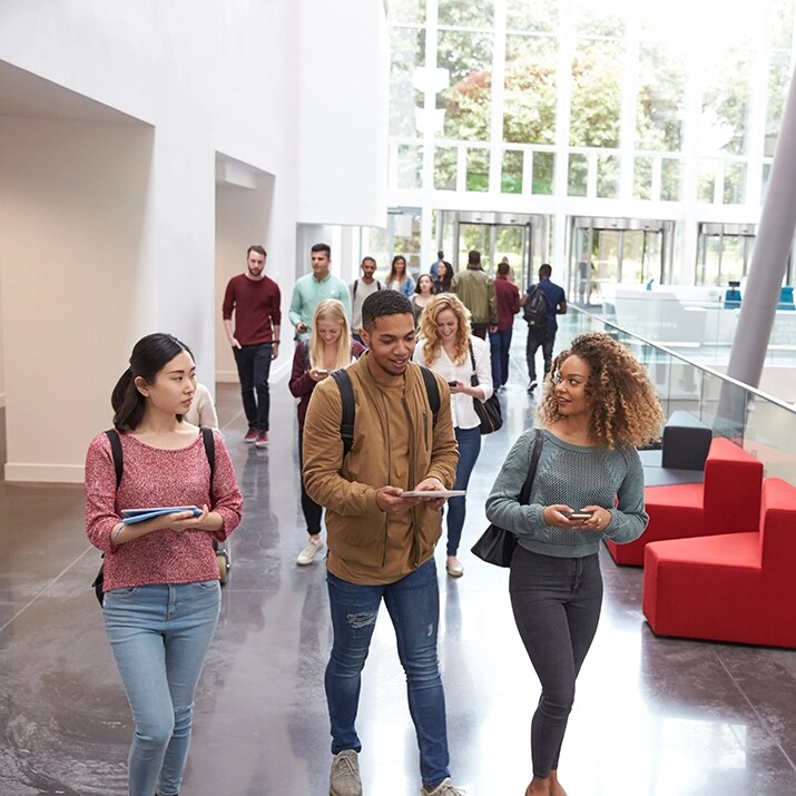 طلاب يمشون أمام مبنى جامعي أثناء رحلة التحضير للاختبار طلاب يمشون أمام مبنى جامعي أثناء رحلة التحضير للاختبار