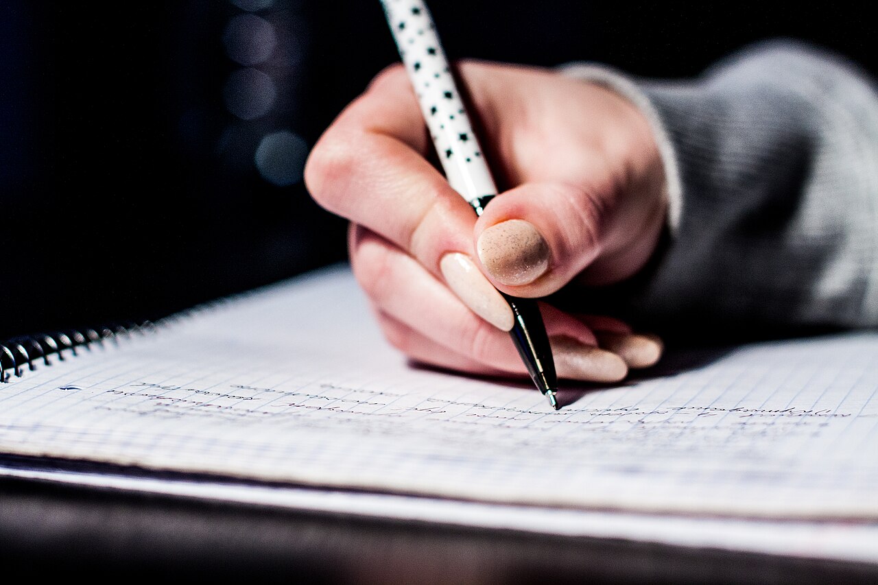 A graduate student takes notes while drafting a research plan