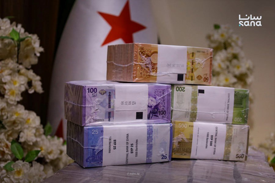 Newly printed Syrian pound banknotes in sealed Central Bank bundles beneath the Syrian flag
